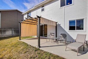 A covered patio with outdoor furniture, a pergola, and a wooden fence.