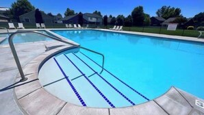 A swimming pool with clear blue water, a curved edge, and a tiled deck.