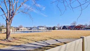 A residential area with houses, a fenced yard, and a tree.