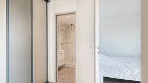 Een moderne slaapkamer met een bed, inloopkast en douchegedeelte.