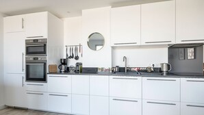Een moderne keuken met witte kasten, roestvrijstalen apparatuur en een zwart aanrecht.