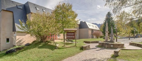 A building with a paved entrance, a signboard, and a stone monument in the center.