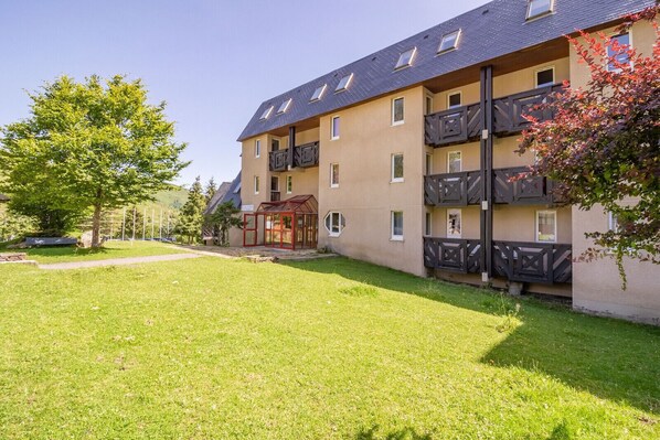 A multi-story building with balconies, a covered entrance, and a well-maintained lawn.