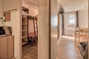 A compact room with bunk beds, a desk, a chair, and a television.