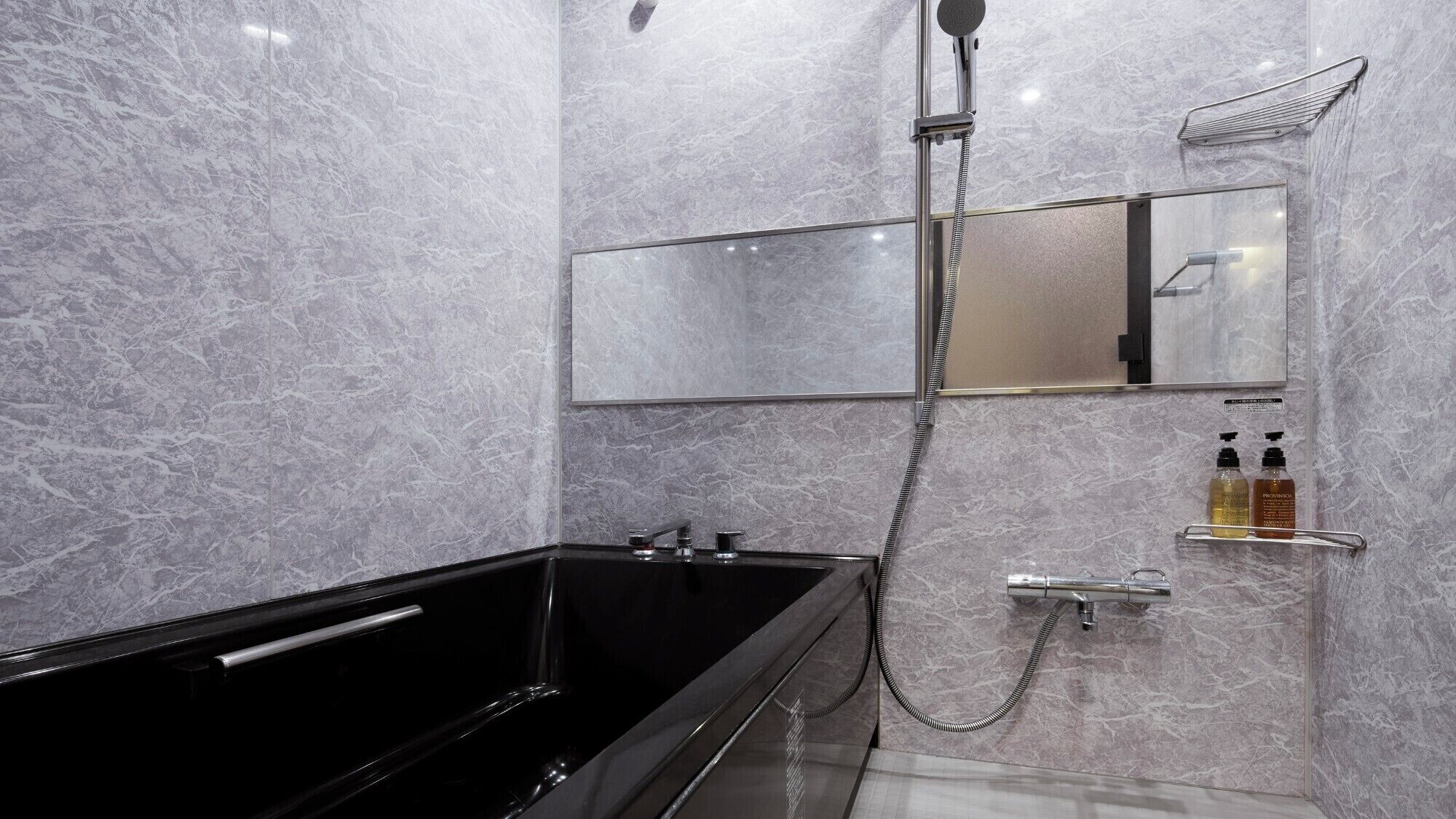 Een moderne badkamer met een zwart bad, een douche met glazen wanden en marmeren wanden.
