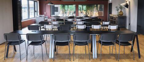 A conference room with a long table and chairs, large windows, and a modern ceiling design.