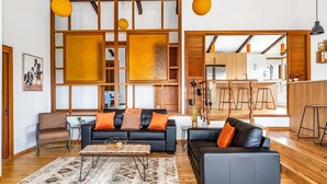 A modern living room with a black leather sofa, a wooden coffee table, and a patterned rug.