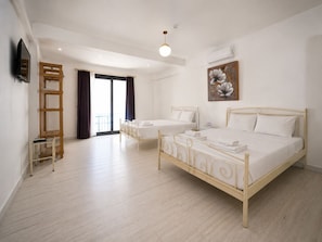 A hotel room with a large bed, a smaller bed, a TV, a painting, and a balcony. - Kybele Alacati (Cesme)