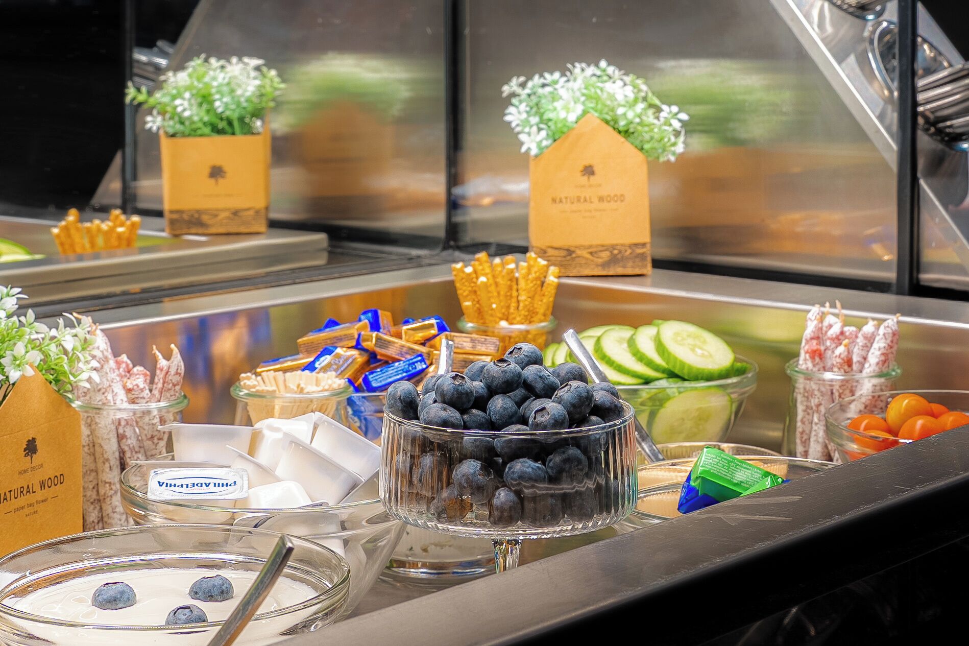 A buffet with various food items including blueberries, sliced cucumbers, and cheese sticks.