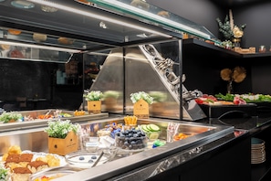 A buffet with various food items and a glass display case. - We rooms Hotel (Karben)