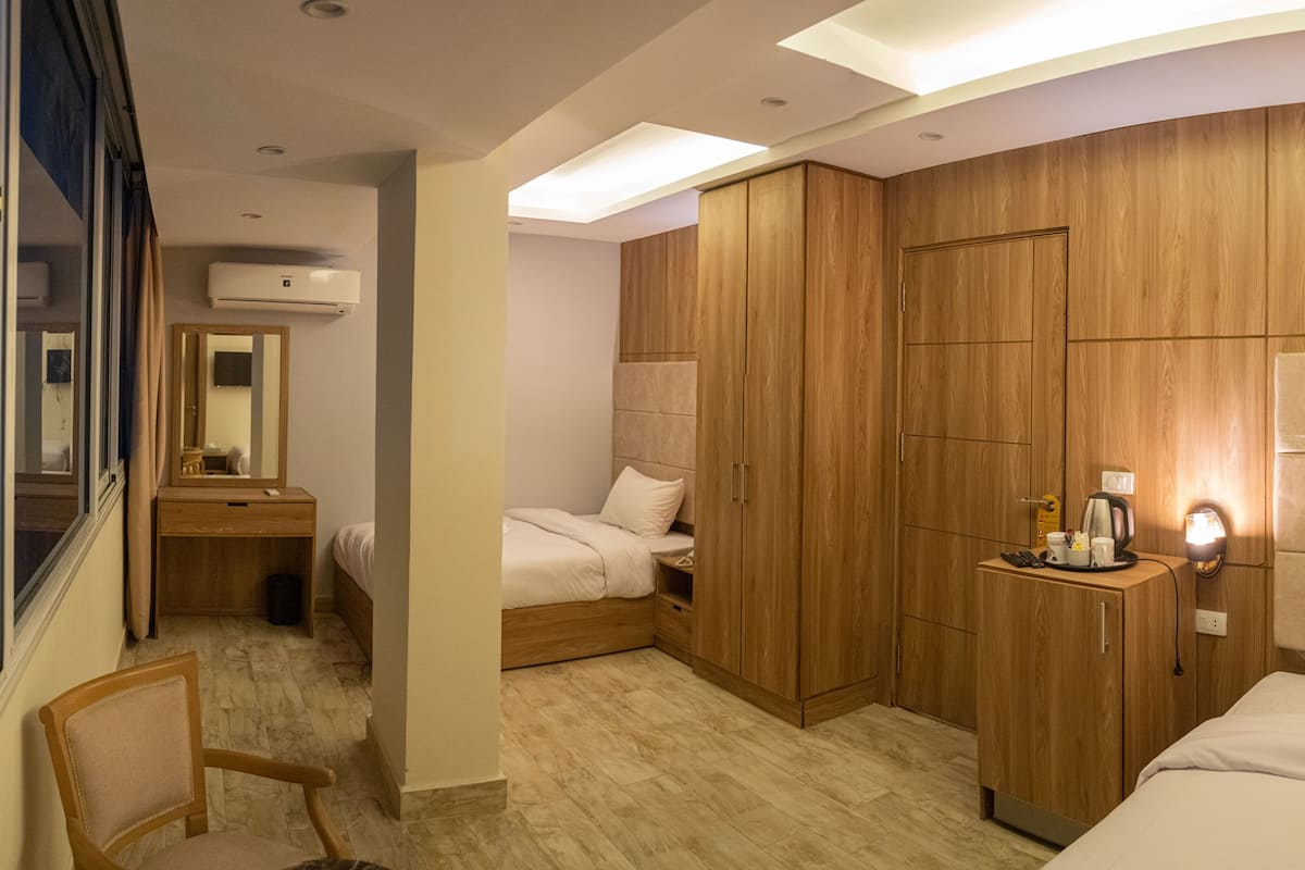 Habitación de hotel con cama, escritorio, silla, armario y espejo.