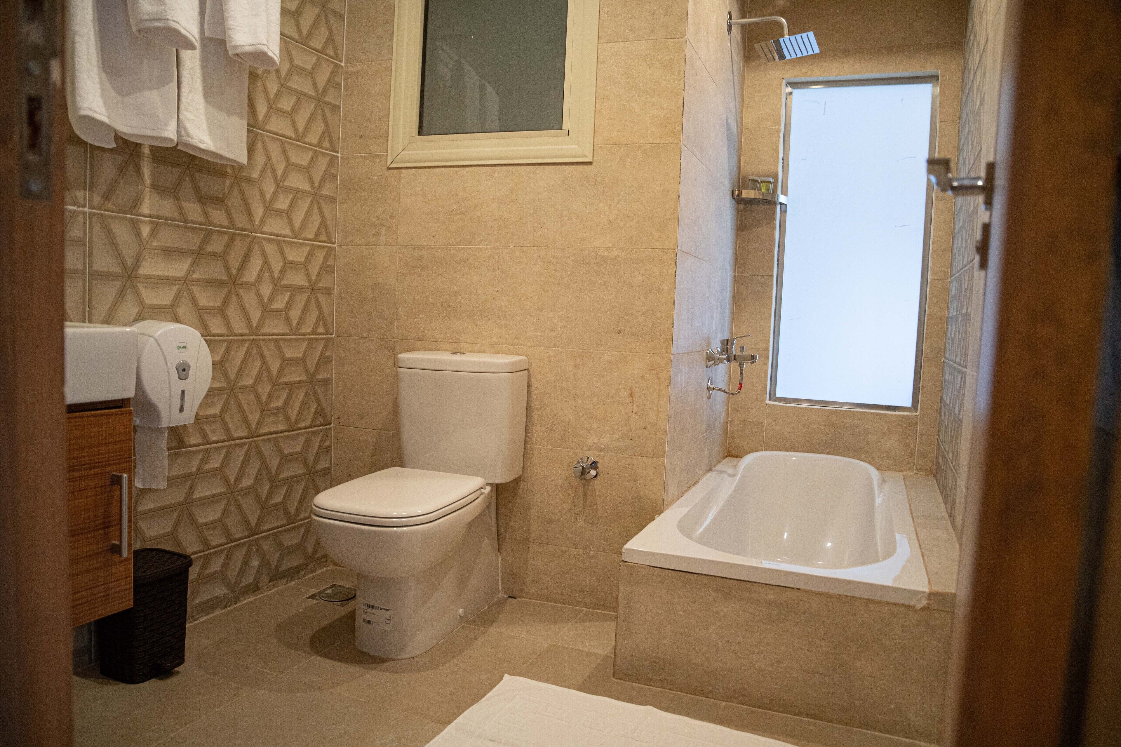Un baño con inodoro, bañera y secador de manos.