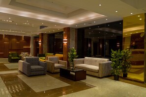 A modern lobby with a marble floor, a sofa, armchairs, a coffee table, and potted plants. - Nine Pyramids View Hotel (Giza)