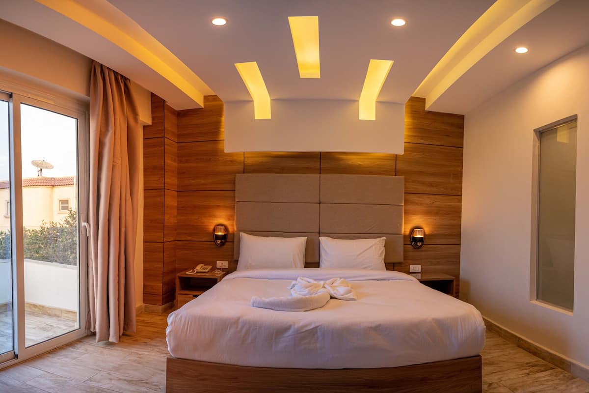 Una habitación de hotel moderna con una cama grande, paneles de madera y luces empotradas en el techo.