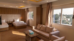 A modern hotel room with a large bed, a sofa, a coffee table, and a TV. - Nine Pyramids View Hotel (Giza)