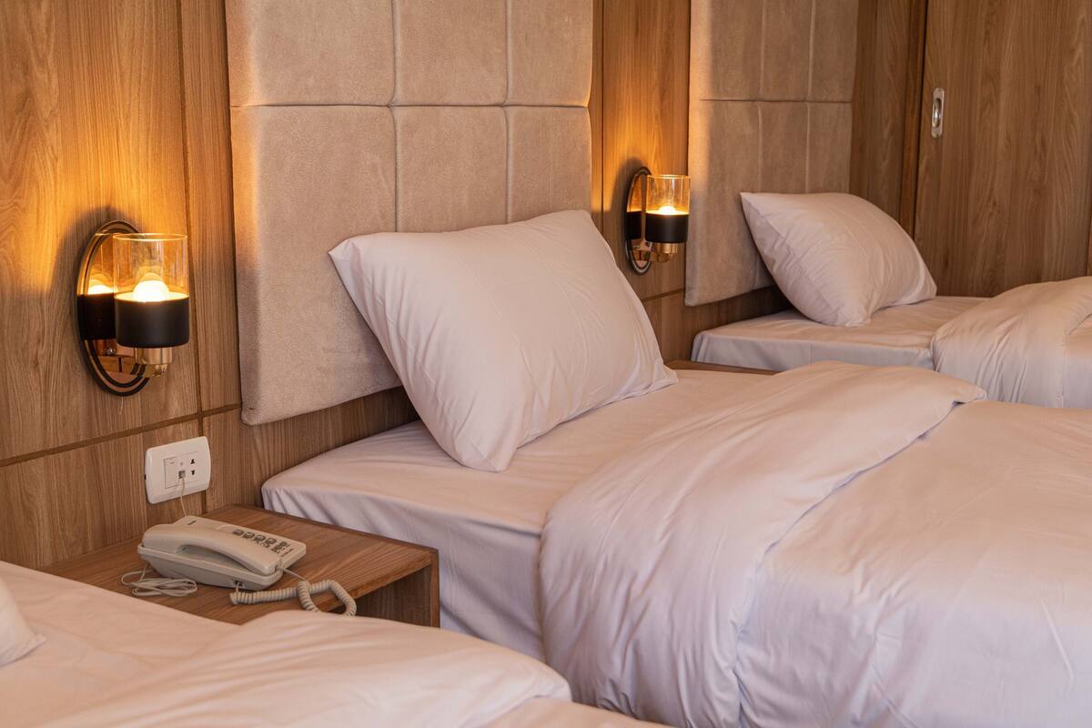 Habitación de hotel con dos camas, teléfono en la mesita de noche y lámparas de pared.