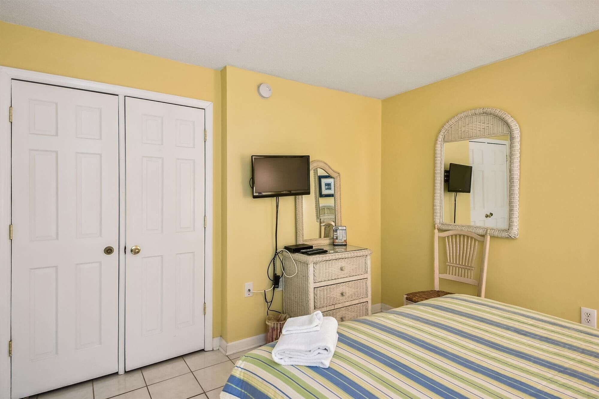Quarto de hotel com cama, penteadeira, televisão e espelho.