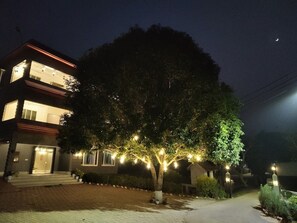 Un immeuble à plusieurs étages, doté d’une entrée bien éclairée et d’un arbre décoré de guirlandes lumineuses.