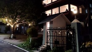 A two-story house with a gated entrance and a tree with lights.