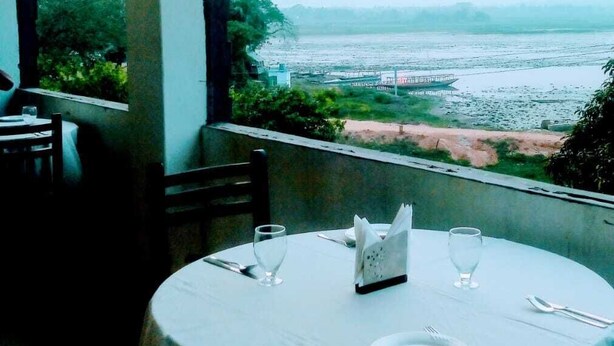 A table set for dining with a view of a river and a boat in the distance.