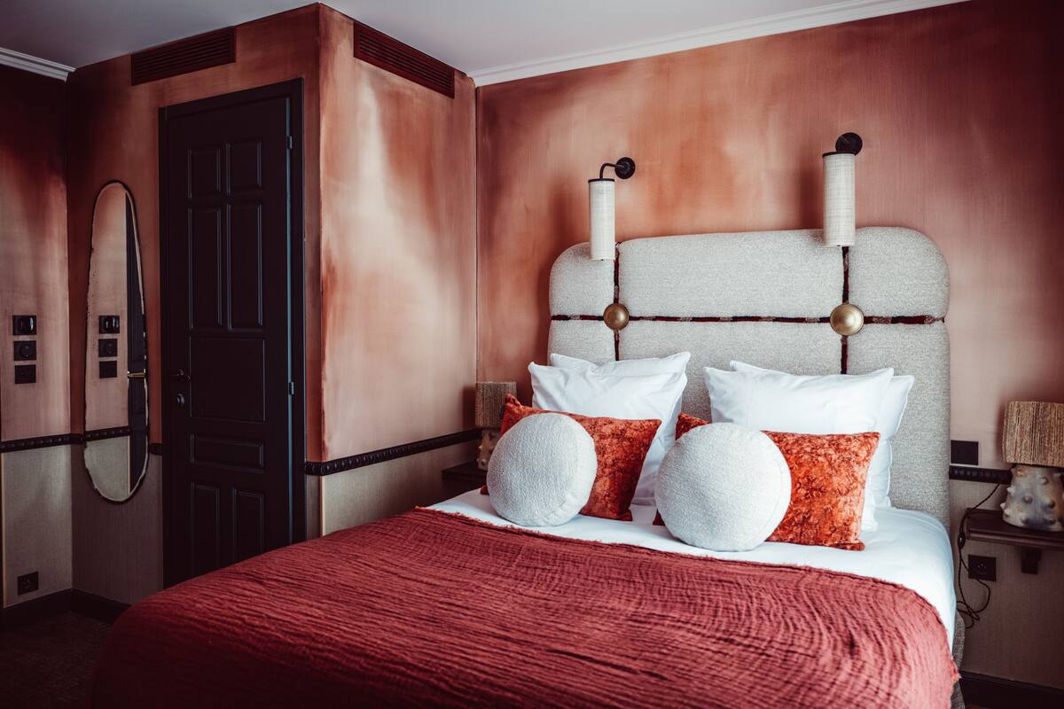 A hotel room with a large bed, a dark wooden door, and a textured wall.