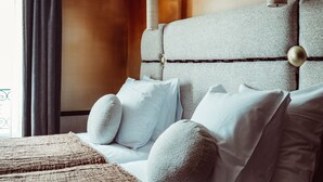 A hotel room with a large bed, a headboard with wall-mounted lamps, and a window with curtains. - Babel Belleville (Paris)