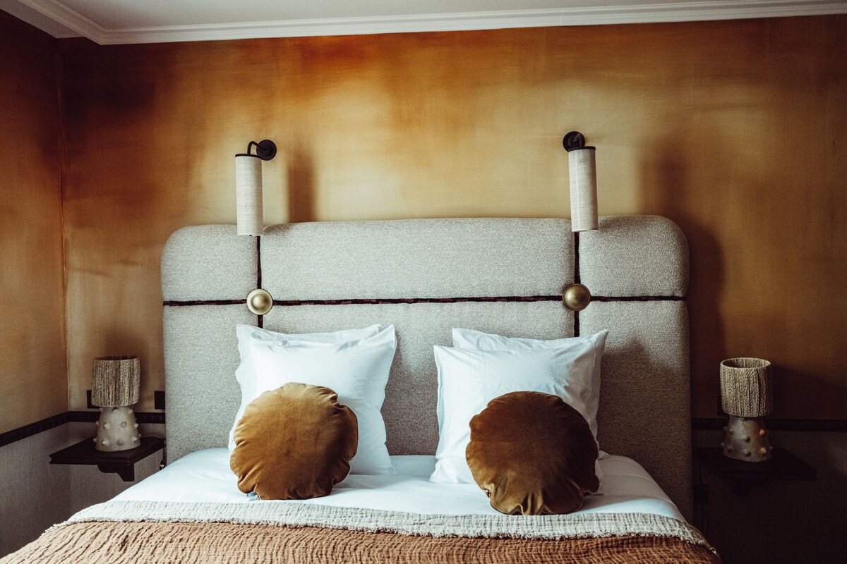 A bed with a headboard, two pillows, and a bedside table with a lamp.