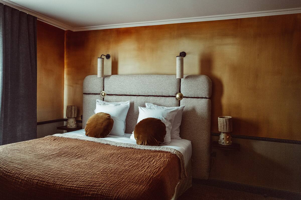 A hotel room with a large bed, two bedside lamps, a nightstand, and a wall-mounted lamp.