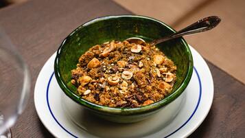 A bowl of granola on a white plate with a blue rim, placed on a wooden table.