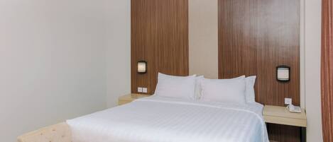 A hotel room with a bed, bedside tables, and an air conditioning unit.