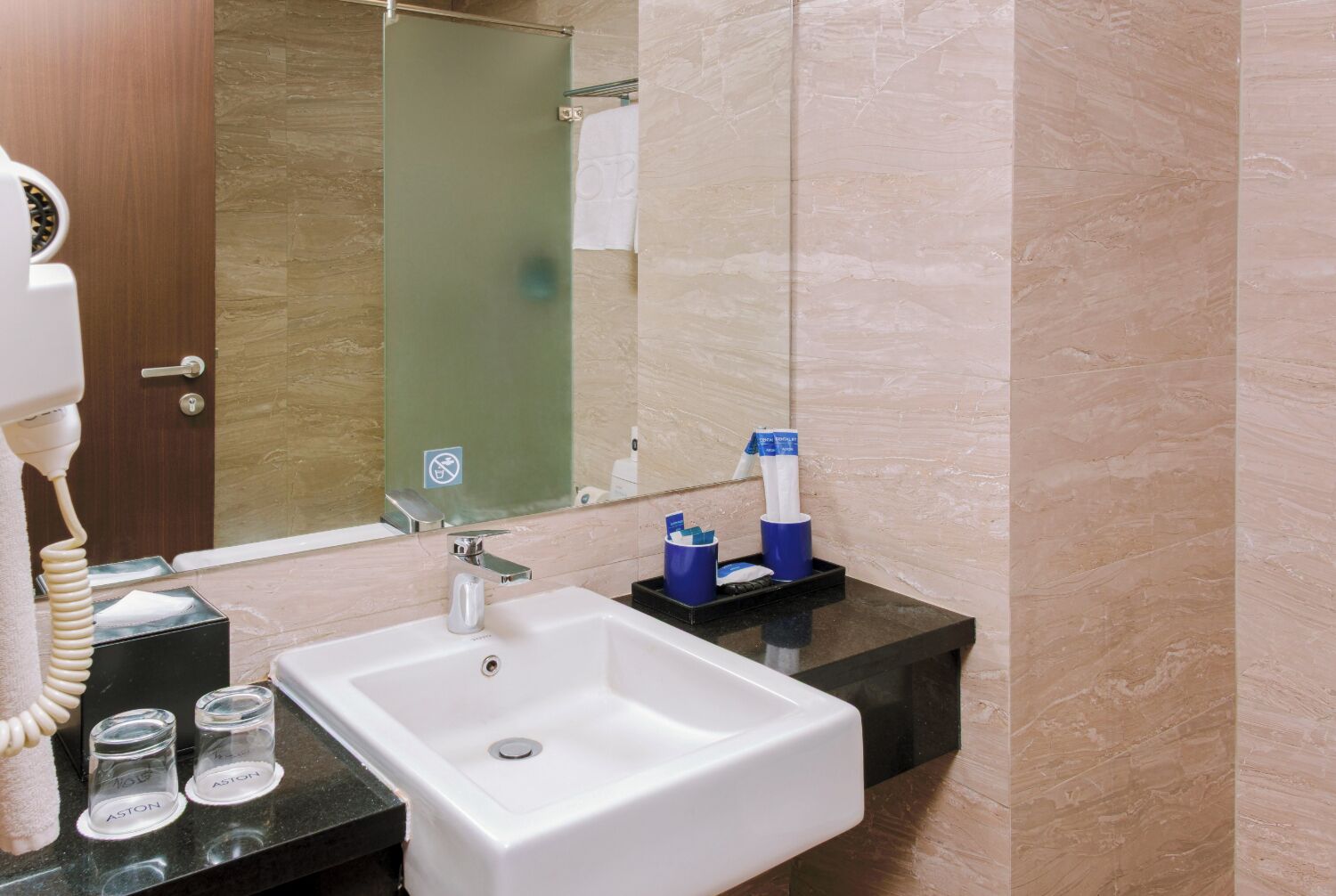 Un baño con lavamanos blanco, espejo, toallero y cabina de ducha de vidrio.