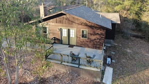Una cabaña de madera con terraza, rodeada de árboles.