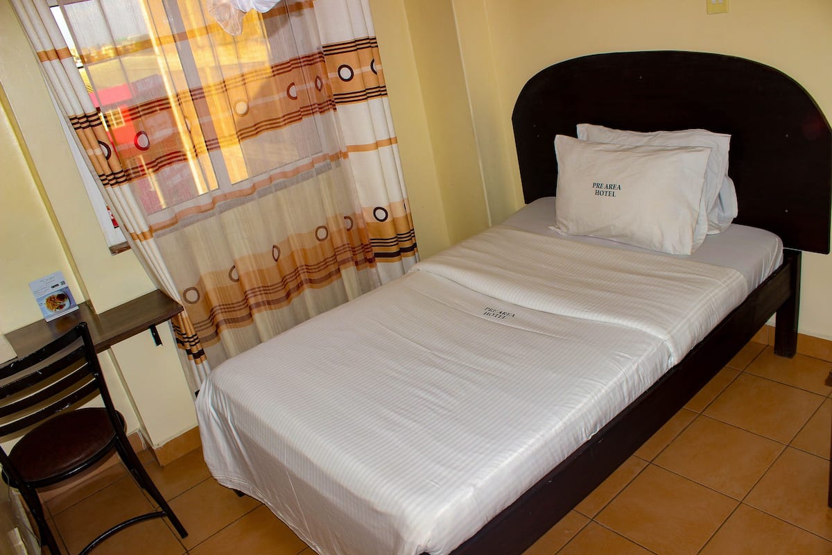 A neatly made bed with a pillow labeled "PREAREA HOTEL" and a striped bedspread.