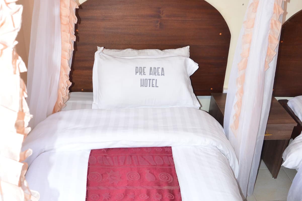 A hotel room with a bed, a headboard, and a red bed runner.