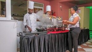 Een buffetopstelling met een kok en bedienend personeel dat gasten bedient.