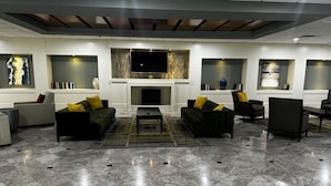 A modern living room with a fireplace, sofas, and a flat-screen TV. - Wingate Houston at Reliant Park & Medical Center (Houston)