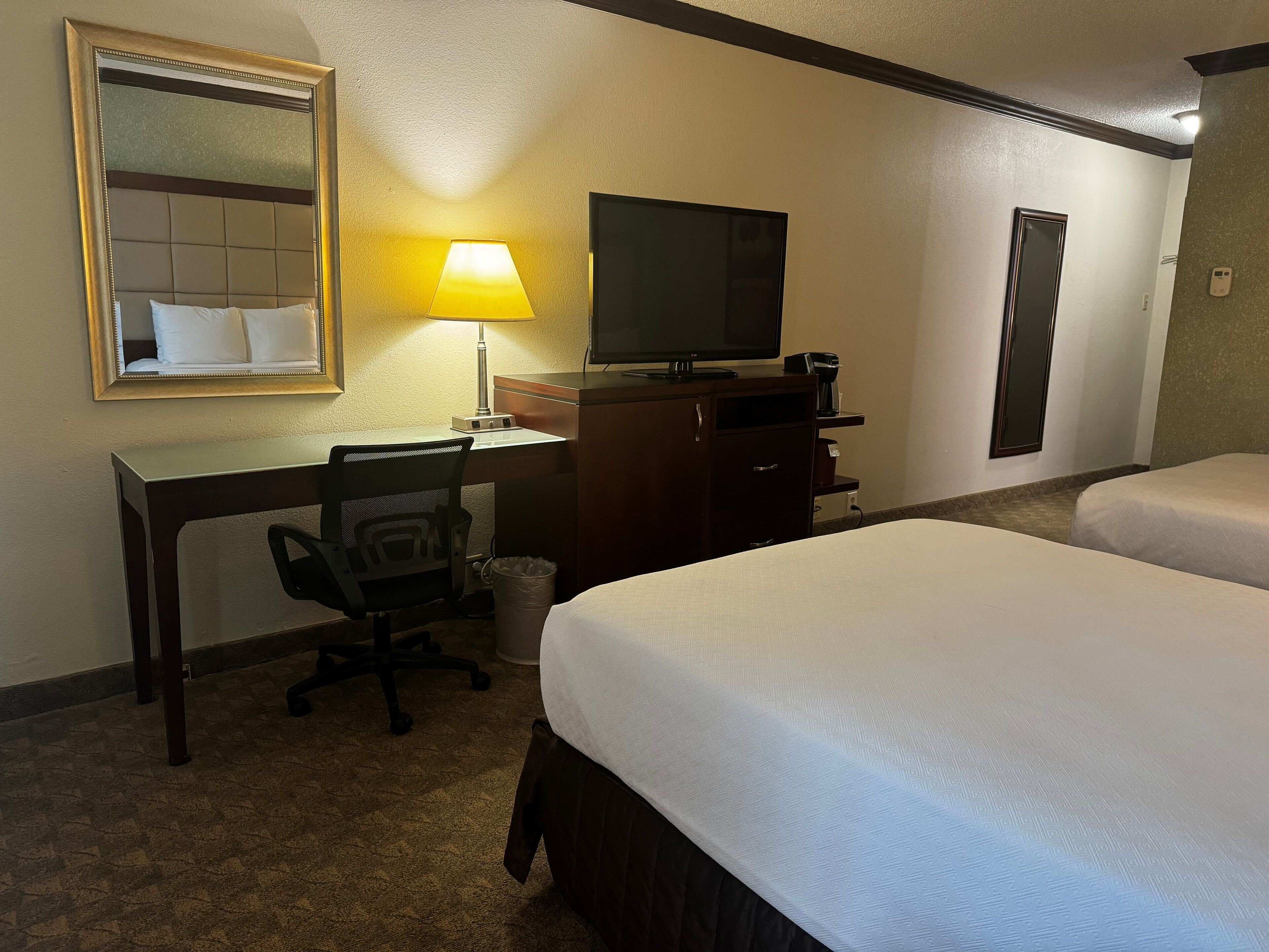 Ein Hotelzimmer mit Bett, Schreibtisch mit Stuhl, Fernseher und Kaffeemaschine.