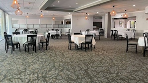 A spacious dining area with multiple tables and chairs, overhead lighting, and a patterned carpet. - Wingate Houston at Reliant Park & Medical Center (Houston)