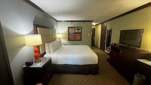 A hotel room with a large bed, bedside lamps, a TV, a dresser, and a painting on the wall. - Wingate Houston at Reliant Park & Medical Center (Houston)