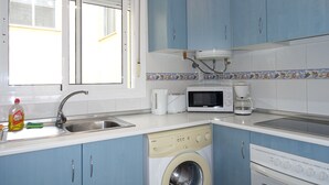 A kitchen with blue cabinets, a washing machine, a microwave, and a coffee maker. - 3 Bed first floor Apartment, communal pool and sea views, wifi. (Gran Alacant)