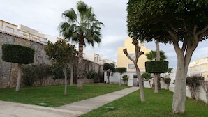 A pathway leading through a well-maintained garden with neatly trimmed hedges and trees. - 3 Bed first floor Apartment, communal pool and sea views, wifi. (Gran Alacant)
