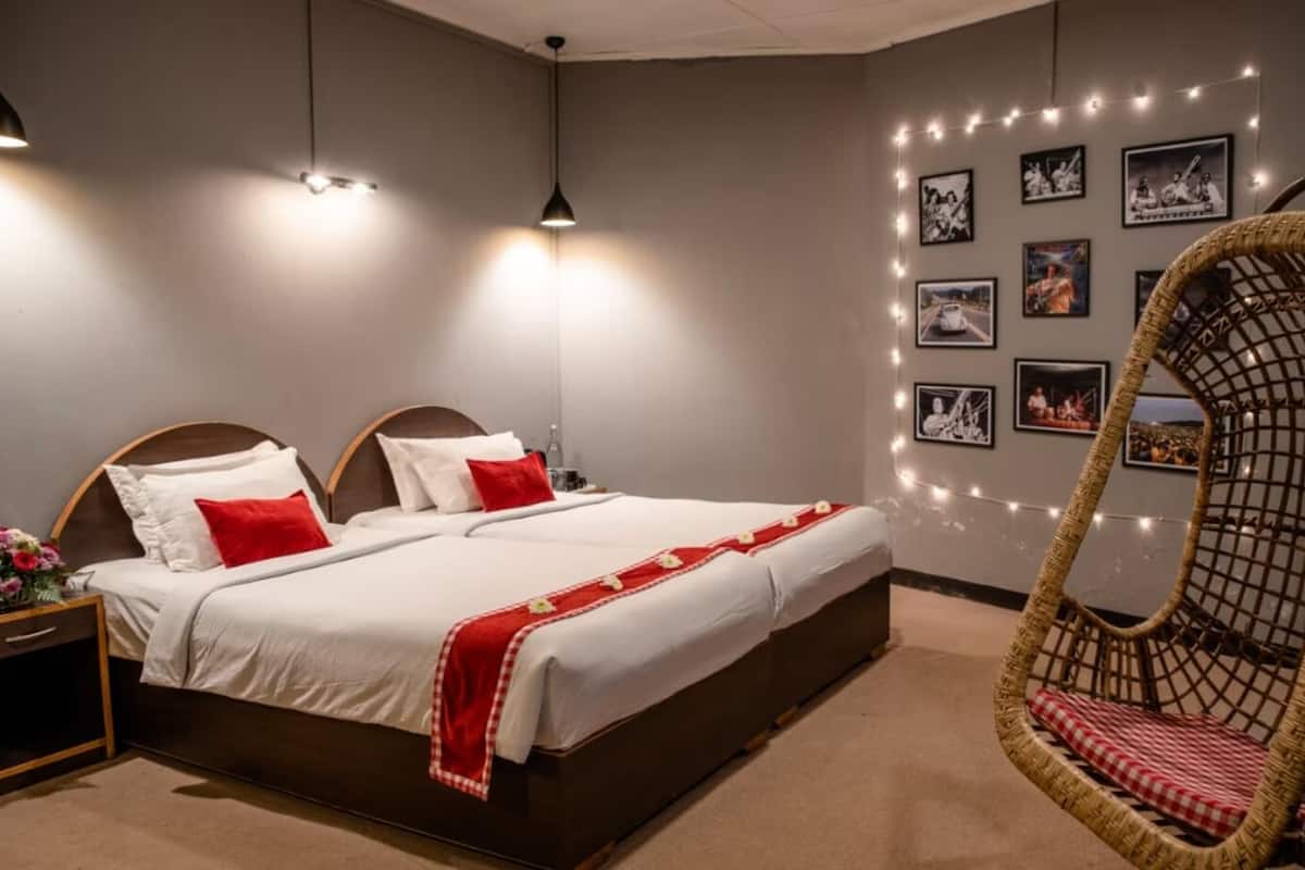 A bedroom with a large bed, a hanging chair, and string lights on the wall.