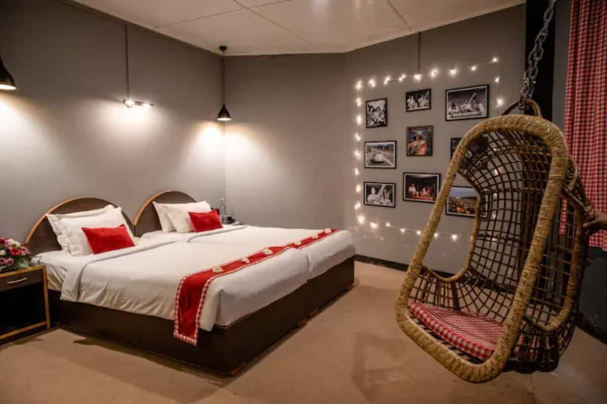 A bedroom with a bed, bedside tables, a hanging chair, and wall-mounted pictures.