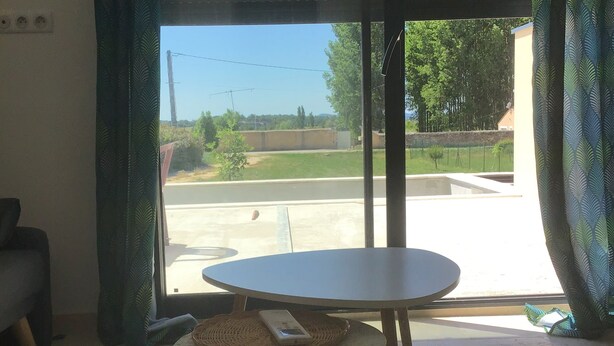 Een kamer met een groot raam, een ronde tafel en een kamerbreed tapijt.
