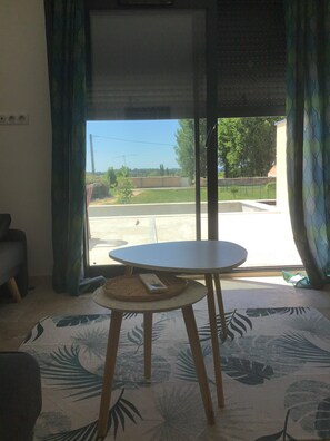 A room with a large window, a round table, and a patterned rug.