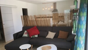 Een moderne woonkamer met een donkergrijze bank, twee kleine witte tafels en een gevlochten mandje op één tafel.