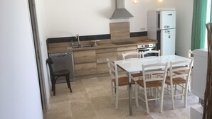 Een moderne keuken met een eethoek. Er is een spoelbak, fornuis, koelkast en houten keukenkastjes.