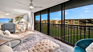 A spacious balcony with a view of a residential area, furnished with a sofa, armchair, and a TV. - Loggerhead Cay 274: Beautiful Condo on the Beach! (Sanibel)
