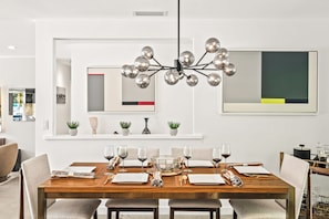 Comedor con mesa de madera dispuesta para seis personas, rodeado de sillas tapizadas.
