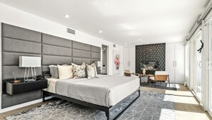 Una camera da letto moderna con un grande letto, un comodino, una televisione e un pannello decorativo a parete.